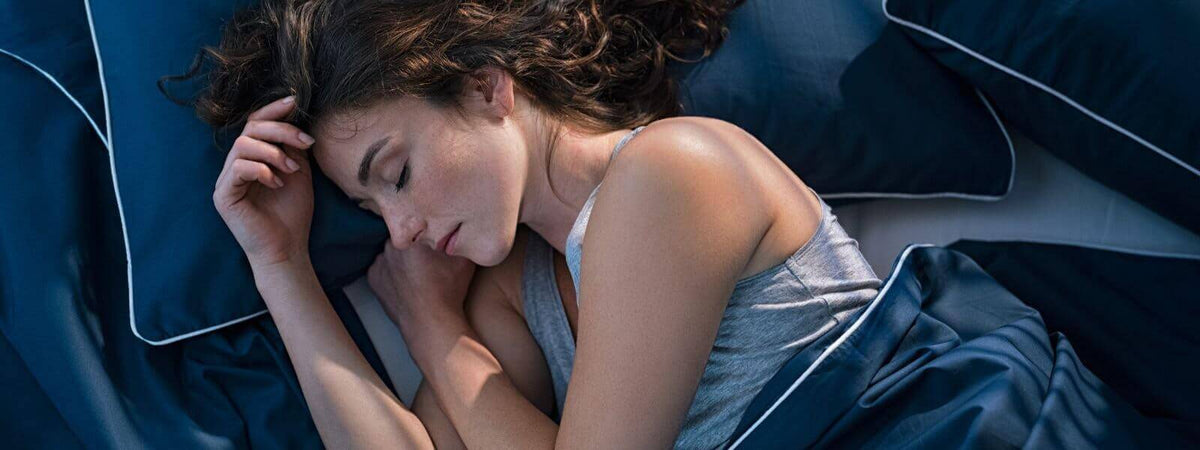 Schlafende Frau auf bequemen Kissen und Bettwäsche, optimale Lichtverhältnisse für eine ruhige Nacht.