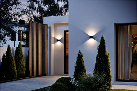 Moderne Hausbeleuchtung am Eingang mit stilvollen Wandleuchten und gepflegtem Garten.