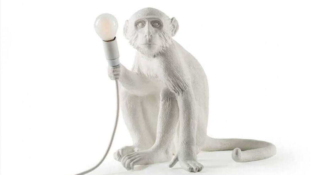 Affenlampe in Form eines sitzenden Affen, der eine Glühbirne hält, moderne und kinderfreundliche Beleuchtung.