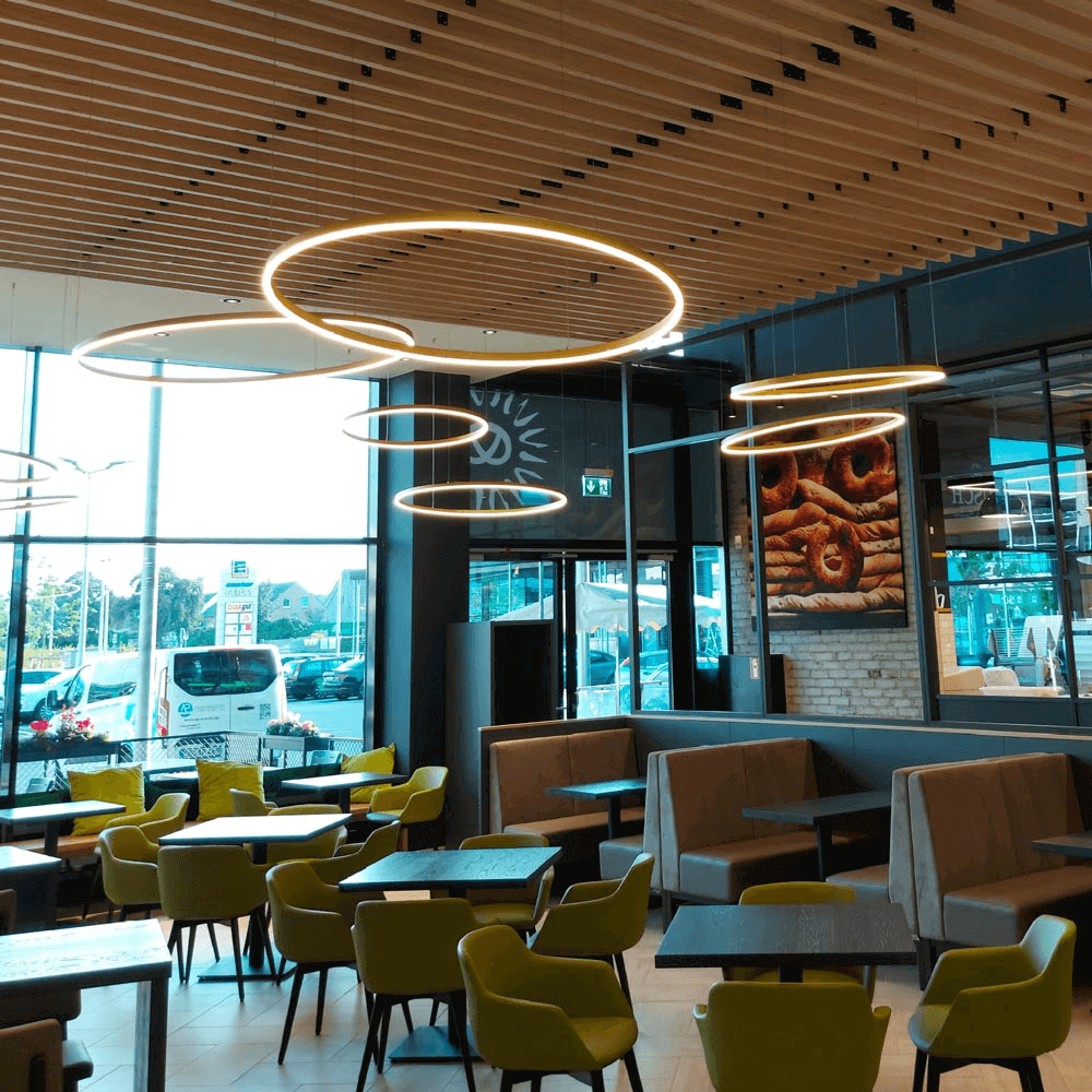 Moderne dimmbare Leuchten in einem einladenden Café mit stilvollen Möbeln und großen Fenstern.