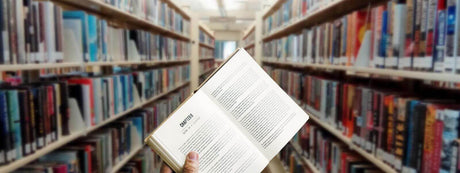Offenes Buch in einer Bibliothek zwischen Regalen voller Bücher, ideal für Konzentration.