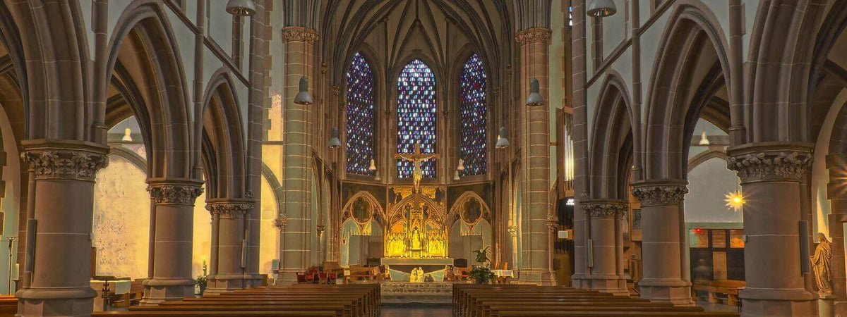 Innenansicht einer Kirche mit beeindruckenden Buntglasfenstern und warmem Licht für optimale Kirchenbeleuchtung.