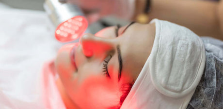 Frau erhält Lichttherapie für Hautbehandlung mit rotem Licht, entspannt und verjüngt.