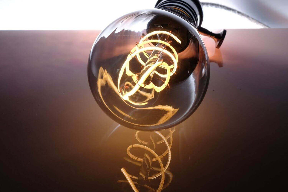 Energiesparen mit LED-Beleuchtung: Glühbirne reflektiert warmes Licht auf einer glatten Oberfläche.