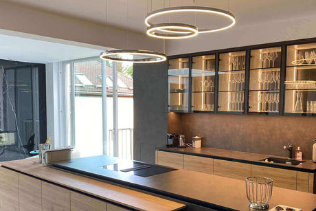 Moderne Küche mit beleuchteter Kücheninsel und eleganten Hängeleuchten.