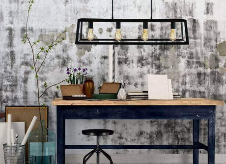 Pendelleuchte im Vintage Style über einem Holztisch mit kreativen Accessoires und Pflanzen im Hintergrund.