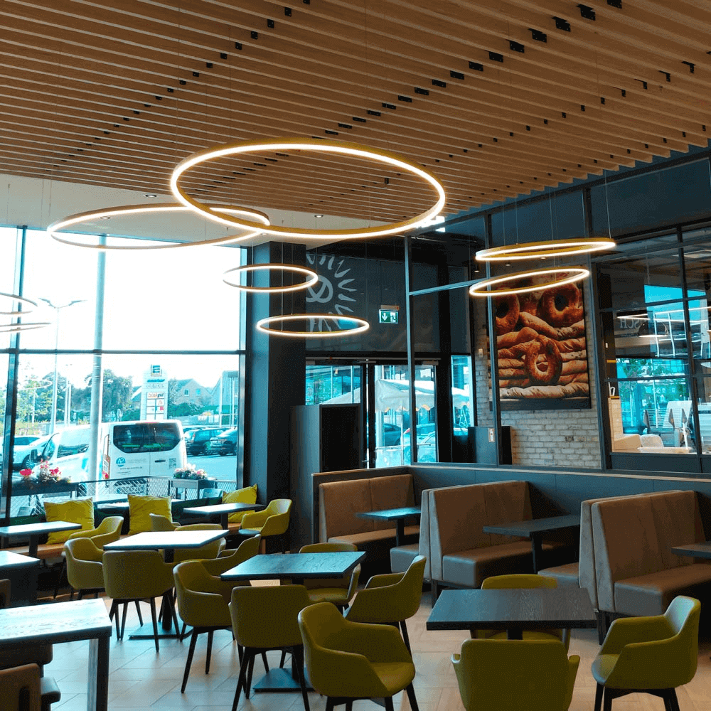 Moderne dimmbare Leuchten in einem einladenden Café mit stilvollen Möbeln und großen Fenstern.