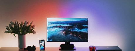 Moderne Büroansicht mit Philips Hue Beleuchtung, Monitor, Smartphone und Vase mit Tulpen.