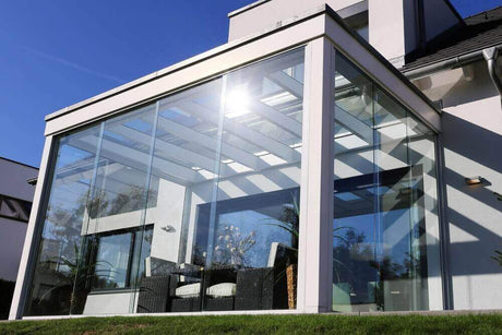 Moderne Wintergarten mit Glasfront und eleganter Beleuchtung unter freiem Himmel.