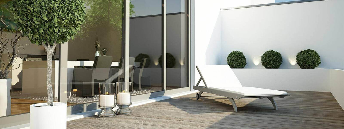 Heller Balkon mit Pflanzen, Liegestuhl und stimmungsvollem Licht für entspannende Sommernächte.