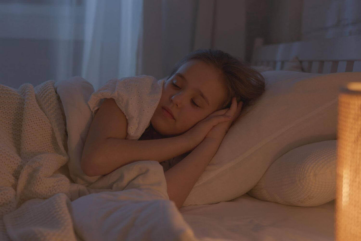 Schlafendes Kind in einem gemütlichen Bett mit einem Nachtlicht, das sanftes Licht spendet.