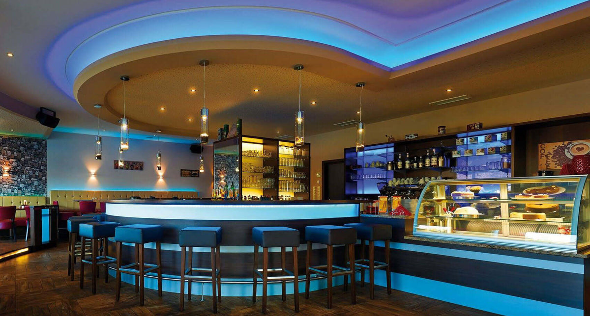 Moderne Bar mit blauer LED-Beleuchtung und stilvollen Sitzplätzen für ein einladendes Ambiente.