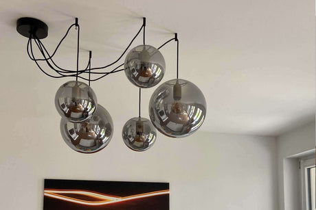 Moderne Deckenleuchte mit fünf gläsernen Lampen, die stilvolle Beleuchtung im Raum schaffen.