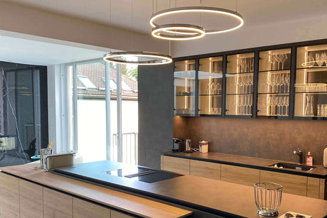 Moderne Küche mit stilvollen Pendelleuchten und eleganter Holzoberfläche auf der Kücheninsel.