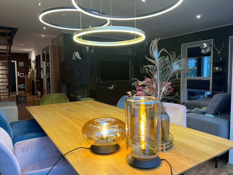 Modernes Esszimmer mit Holz-Esstisch und stilvollen Lampen, eingerichtet für gesellige Abende.