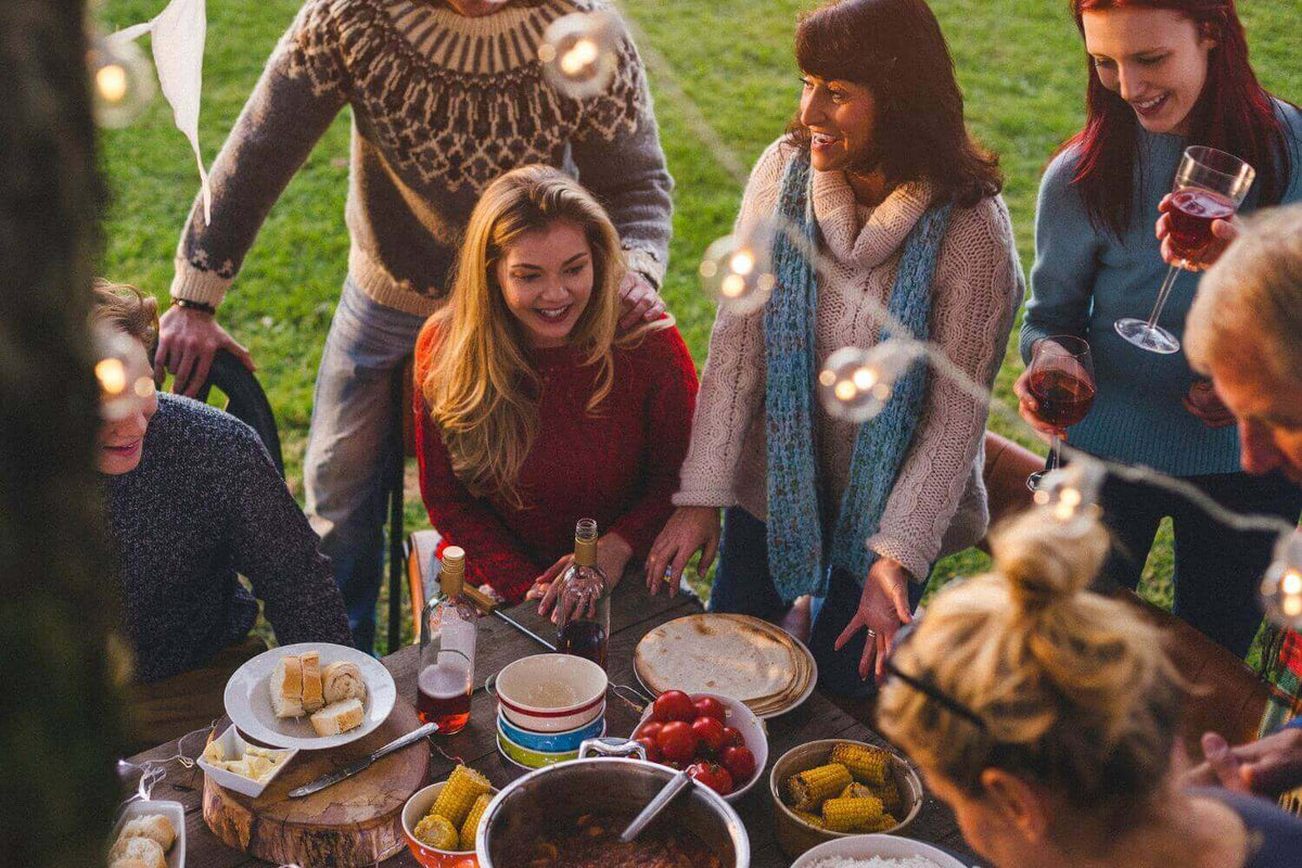 Freunde genießen eine Gartenparty mit leckerem Essen und stimmungsvollem Licht im Freien.