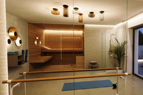 Moderne Wellness-Oase mit eleganten Lampen, Sauna, Glasdusche und Yoga-Matte für entspannende Momente.