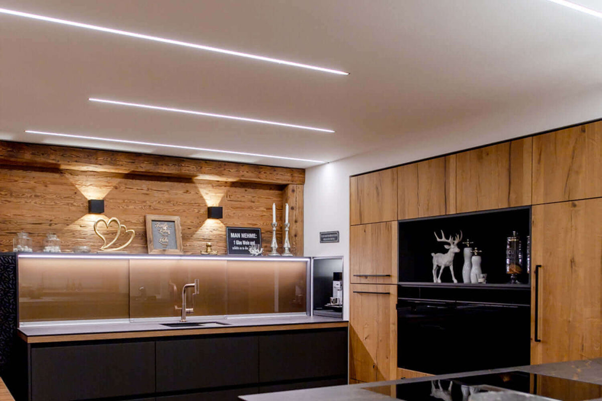 Moderne Küche mit indirekter Beleuchtung, Holzdetails und eleganter Einrichtung für großzügiges Raumgefühl.