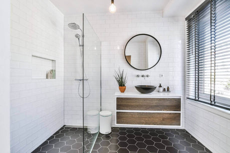 Modernes Badezimmer mit Dusche, runder Spiegel und stilvollem Waschbecken in neutralen Farbtönen.