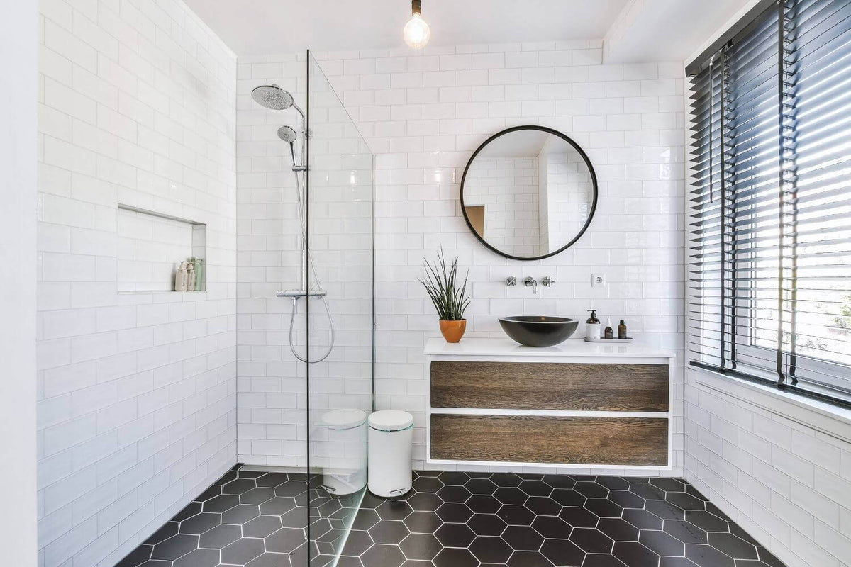 Modernes Badezimmer mit Duschbereich, runder Wandspiegel und eleganten Holzmöbeln als Inspirationsquelle für Beleuchtung und Einrichtung.