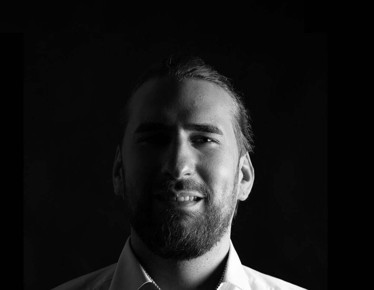 Schwarz-weiß Porträt eines Mannes mit Bart und lächelndem Gesicht, ideal für Artikel über Persönlichkeiten im Business.