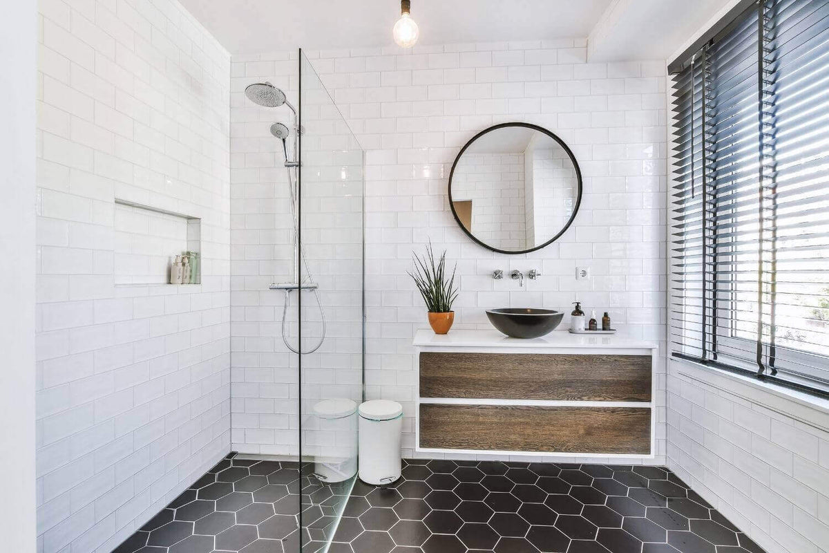 Modernes Badezimmer mit Duschbereich, runder Wandspiegel und eleganten Holzmöbeln als Inspirationsquelle für Beleuchtung und Einrichtung.