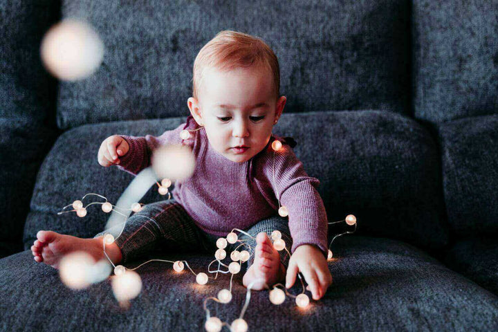 Cozy Lights – Dein Zuhause in warmem Wohlfühllicht erstrahlen lassen, ein Kleinkind spielt mit Lichtern auf einem Sofa.