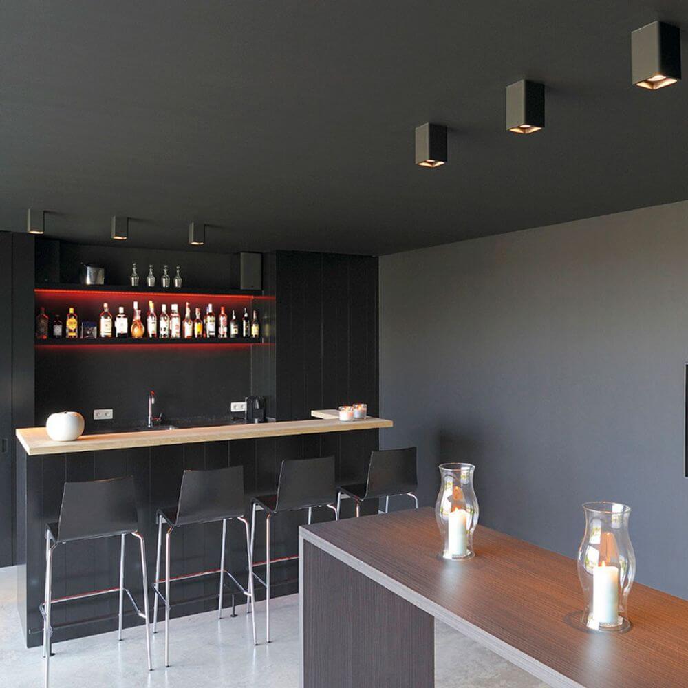 Moderne Bar mit minimalistischer Einrichtung und Deckenbeleuchtung in einem stilvollen Raum.