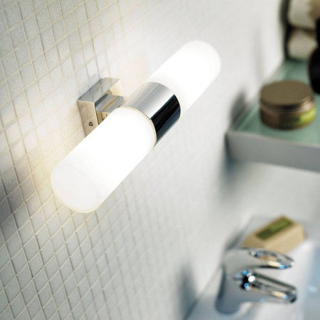 Tangens wall light chrome on bathroom wall in a minimalist design with white light.