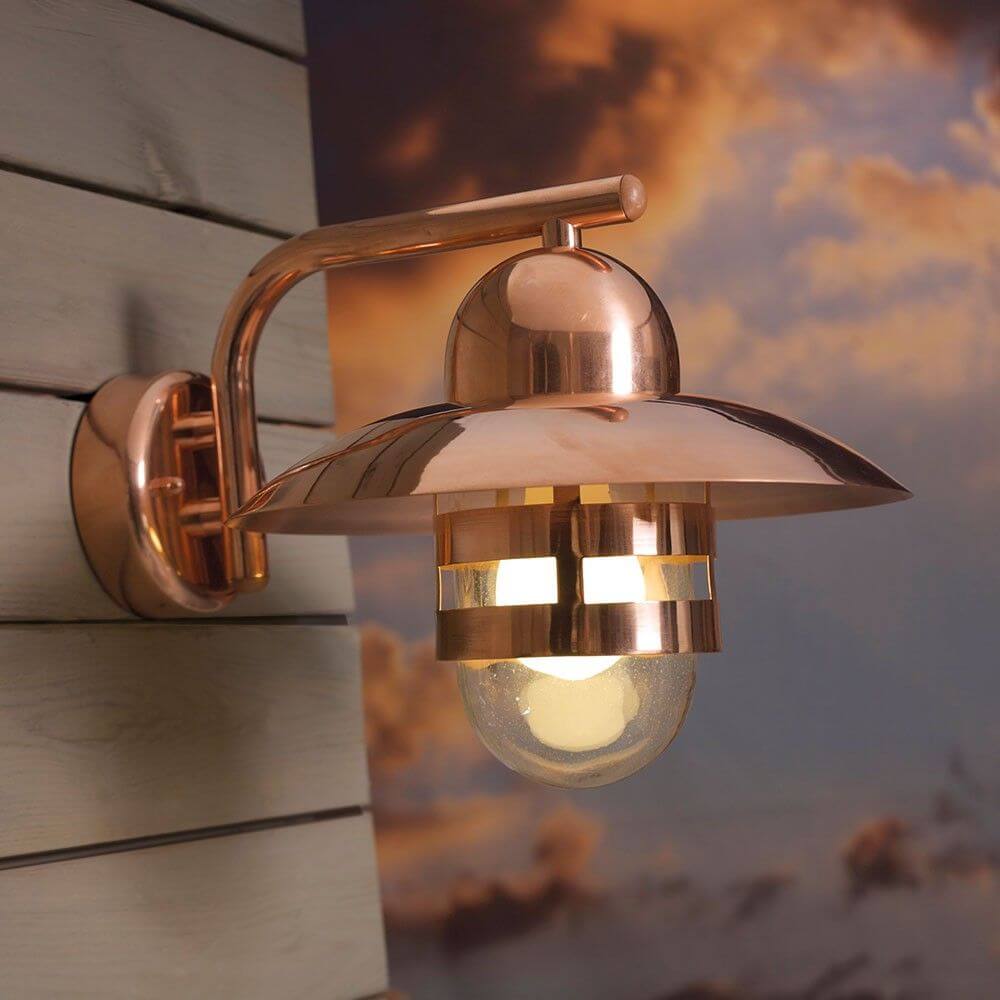 Nibe Außen-Wandleuchte Kupfer an einer Wand montiert, mit einem warmen Lichtschein.