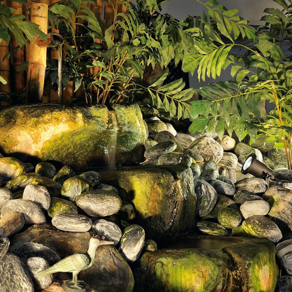 Nautilus Spike XL Strahler beleuchtet einen Steingarten mit Pflanzen und Wasserfall.
