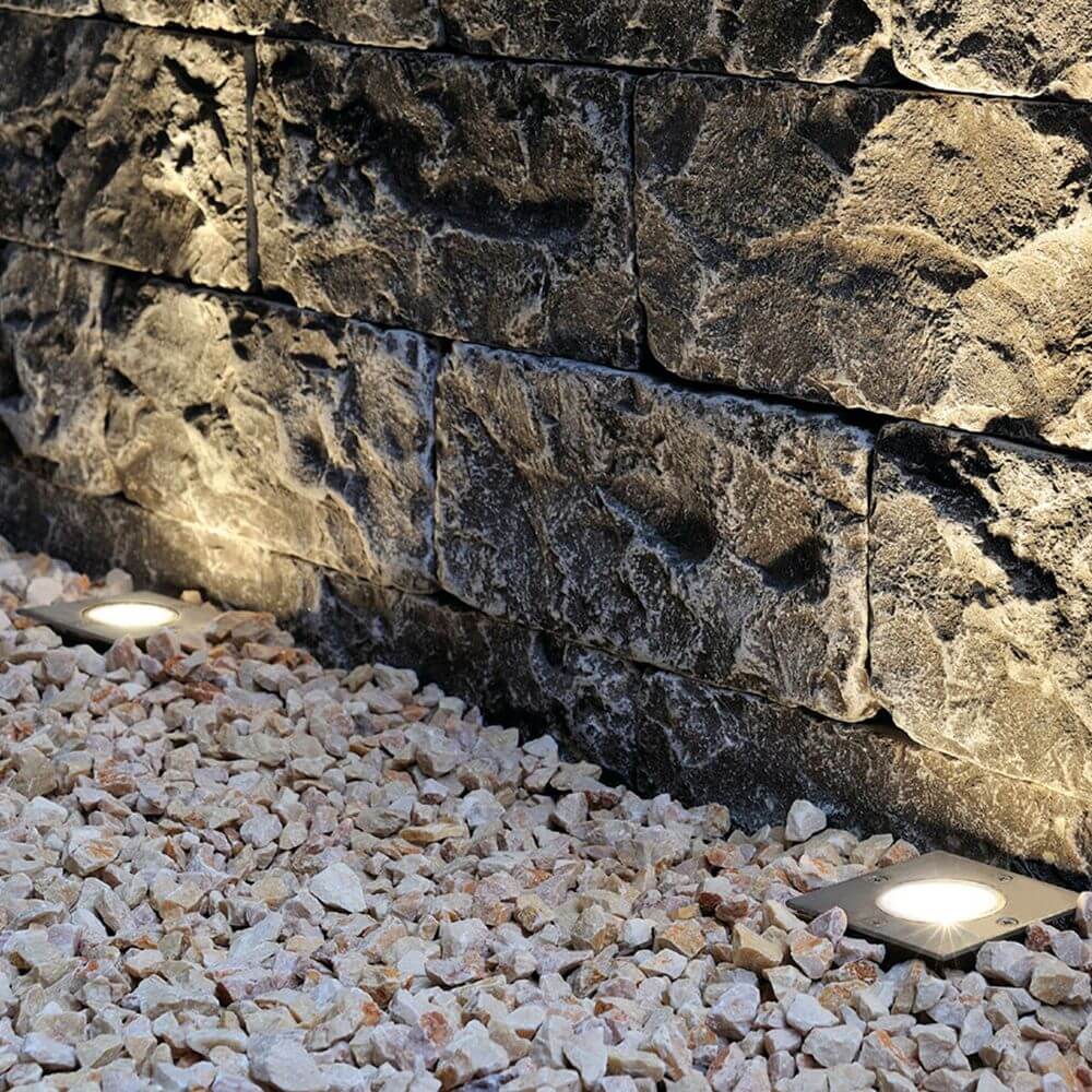 Dasar 115 GU10 Bodeneinbauleuchte eckig Edelstahl IP67 an Steinwand mit Kiesboden.