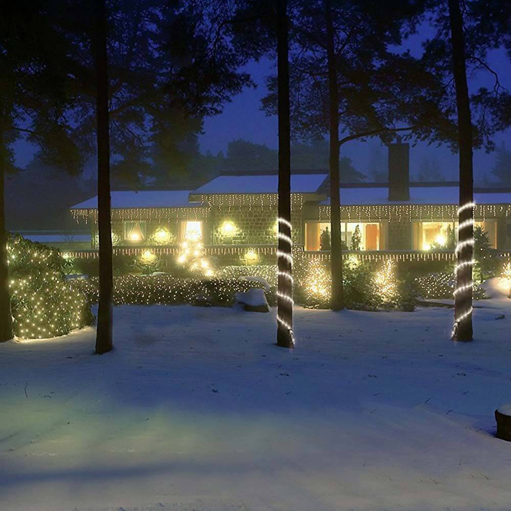 24V LED System Lichtervorhang mit 200 warmweißen LED umgibt ein winterliches, beleuchtetes Haus.
