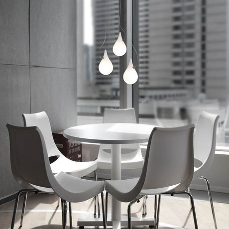 Drop-2XS LED lampada a sospensione tripla Liquid-Light bianca sopra un tavolo rotondo con sedie bianche in un design d'interni moderno.