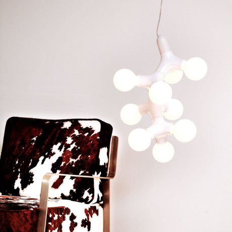 DNA Quattro-9.1 lampada a sospensione nera sopra una sedia moderna con design in pelle bovina.