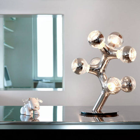 DNA Triple-7 Bordslampa i krom på bordet med stiliga ljuskällor och modern design.
