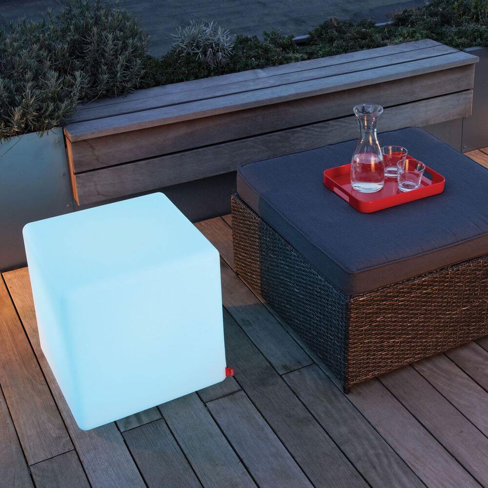 Moree Cube Outdoor LED Sitzwürfel in sanftem Licht neben einem eleganten Gartensofa.