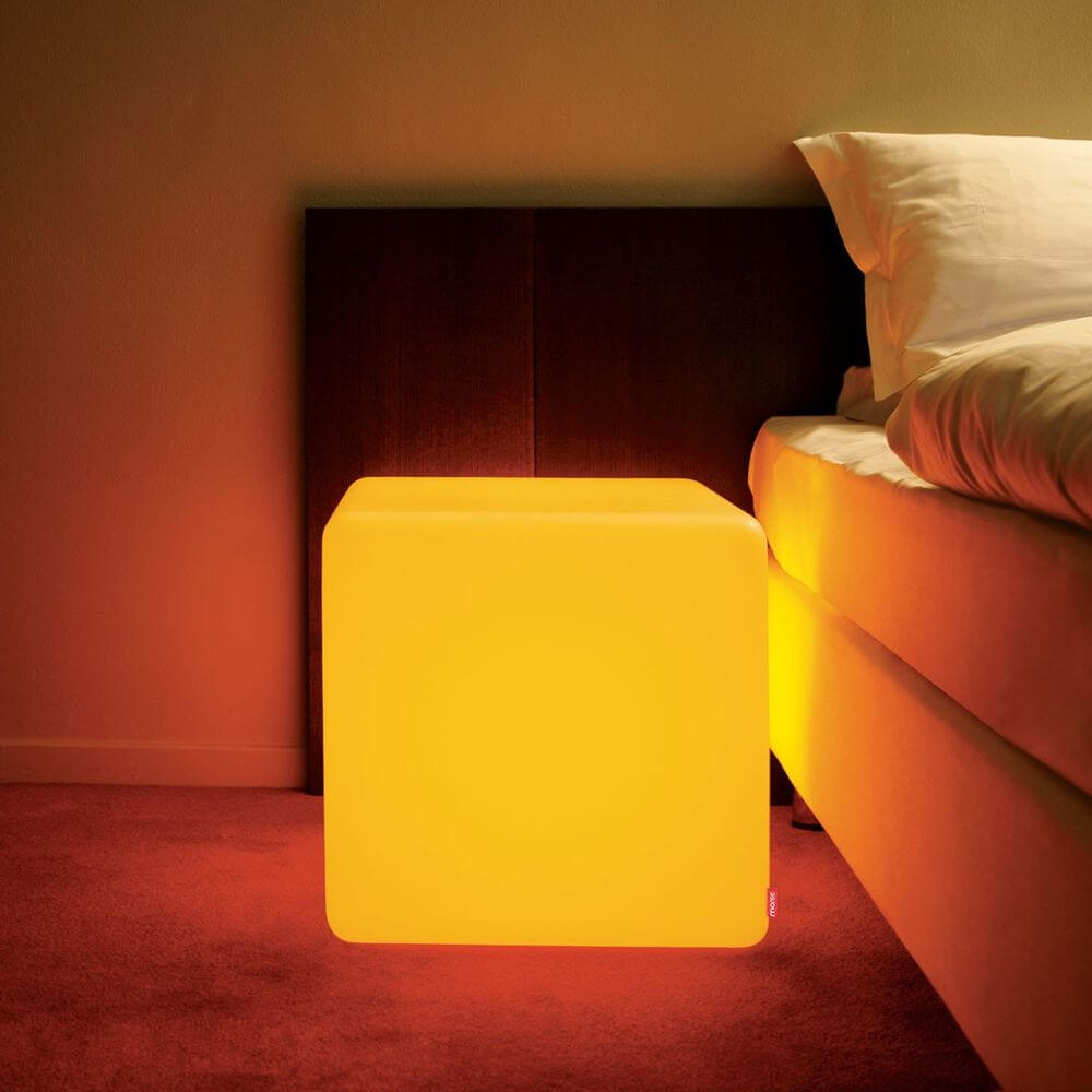 Moree Cube Outdoor LED Sitzwürfel in warmem Gelb als stylischer Nachttisch neben dem Bett.