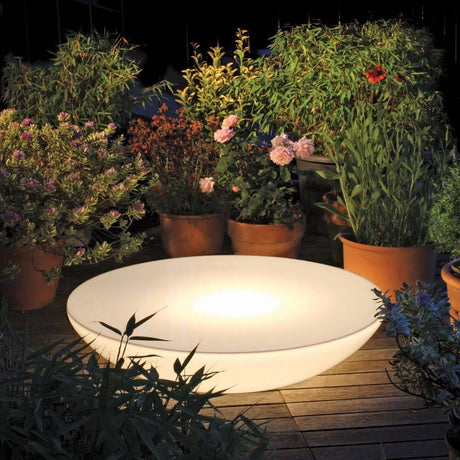 Moree Lounge Variation Outdoor LED lampa stołowa lub ścienna w luksusowej ogrodowej scenerii nocą.