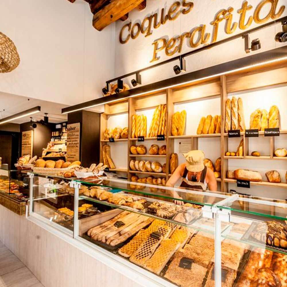 Bäckerei mit ansprechender Brotpräsentation und Verkäuferin hinter dem Verkaufstresen.