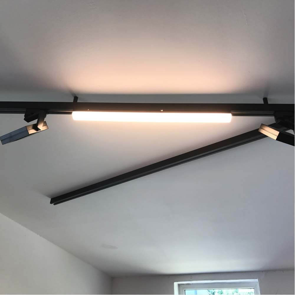 3-Phasen Linienleuchte 2200lm 20W 3000K warm Schwarz an 3-Phasen Schiene installiert, gleichmäßig Raumlicht abgebend.