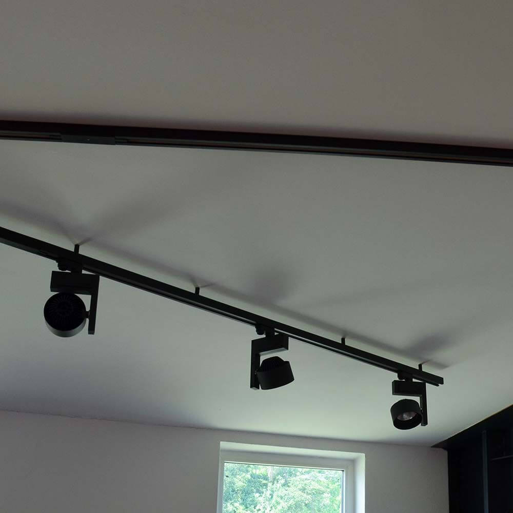 3-Phasen Mittel-Einspeiser Schwarz auf einer Decke mit gerichtetem Licht für effektive Beleuchtung.