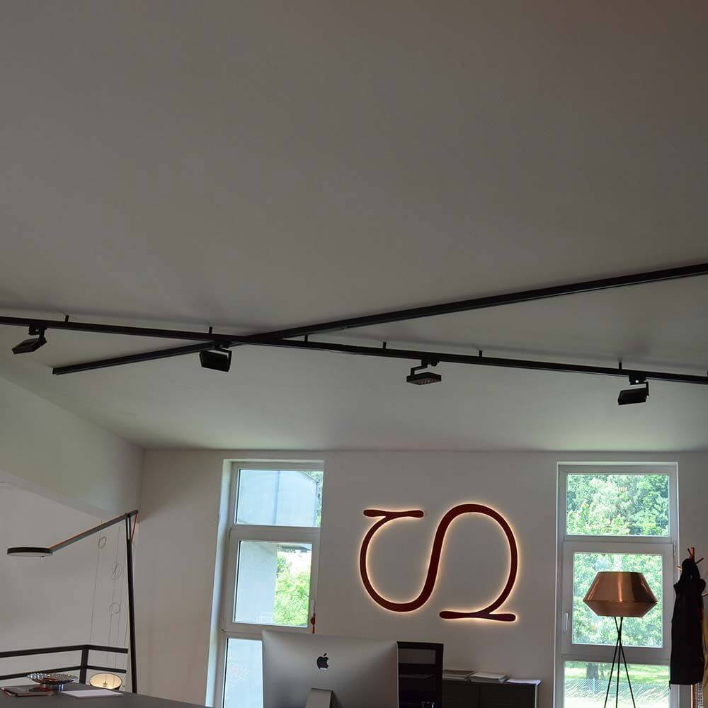 Moderne Büroumbau mit 3-Phasen Lichtschienen und minimalistischer Einrichtung in neutralen Farbtönen.