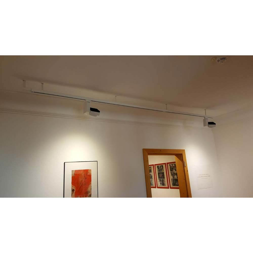 3-Phasen Stromschiene 2m Weiß in einem modernen Raum mit Kunstwerken an der Wand.