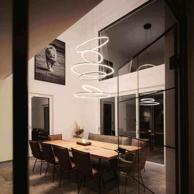 Modernes Esszimmer mit stilvollen runden Lampen und einer großen Holztischanordnung.
