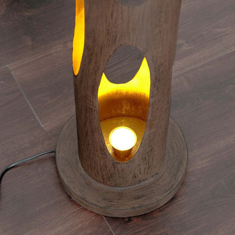 Vista dettagliata della lampada da terra Mascha in ferro marrone-nero-oro con luce dorata all’interno.