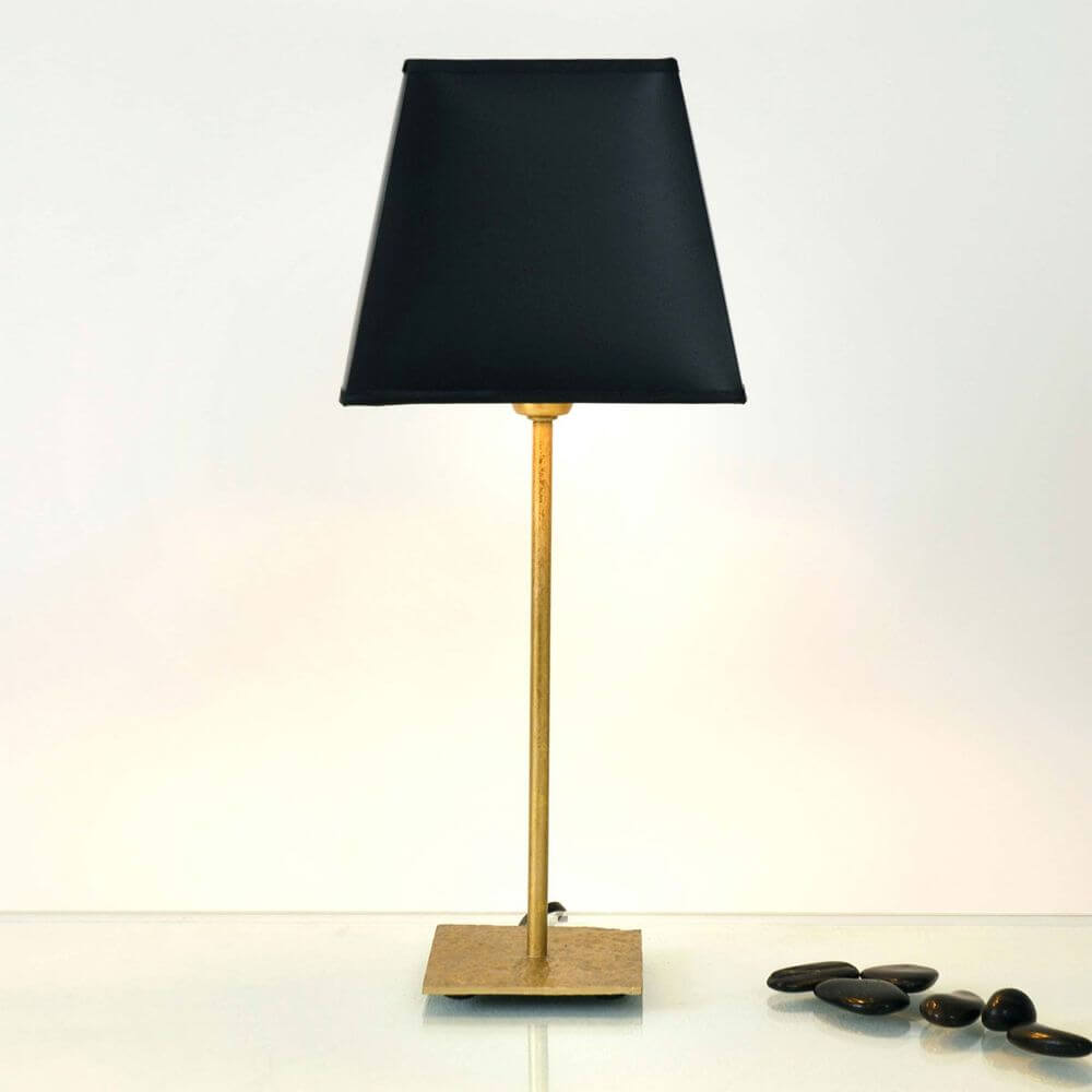 Tischleuchte Mattia Eckig Eisen Gold-Schwarz mit schwarzem Schirm und goldenem Gestell auf glattem Tisch.