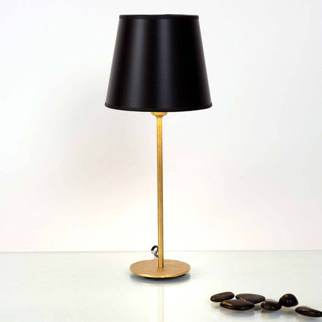 Bordlampe Mattia Rund Eisen Gold-Svart på et bord med svart lampeskjerm og gullfarget base.