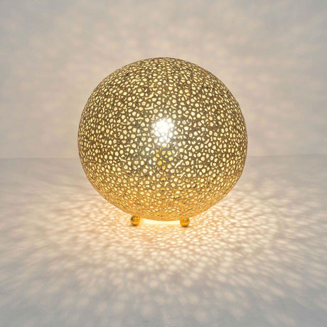 Lampe de table Lily Grande fer doré de forme ronde avec un design filigrane et une lumière chaleureuse.