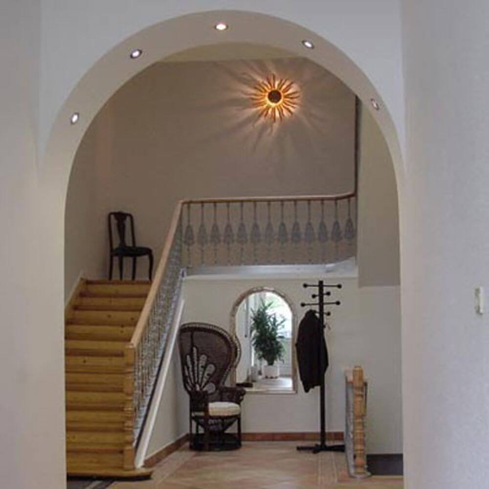 s.luce Diator XL handgeschmiedete Sonne Rost- & Goldfarben in einem modernen Flur mit Treppe